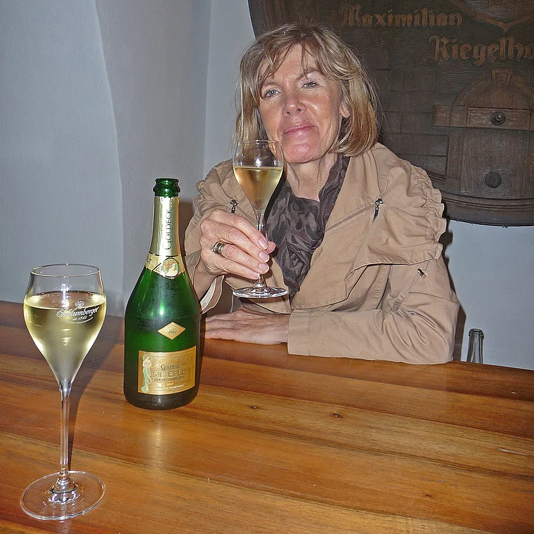Winzerin mit einem Glas Sekt im Weinkeller