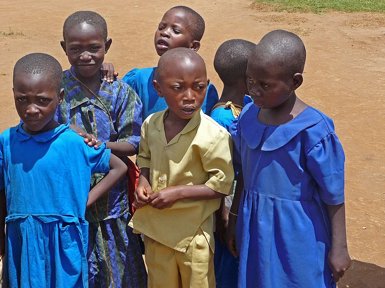 Ruanda kleiner Junge in Schuluniform von Mädchen umgeben