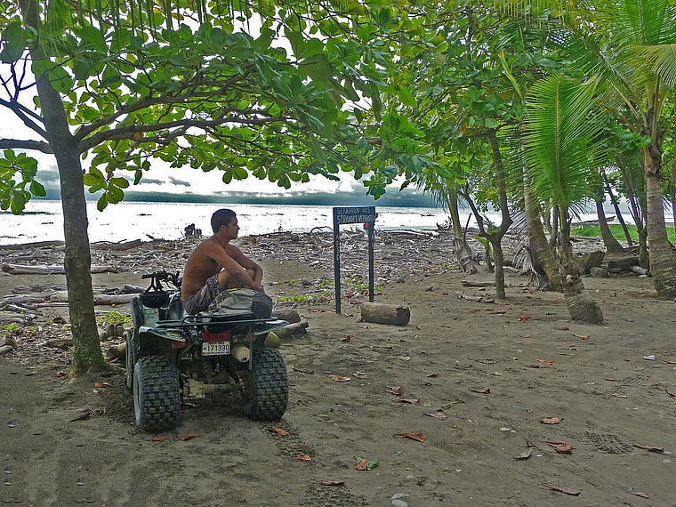 Costa Rica Dominical Schild Befahren des Strandes verboten Junge auf Quad