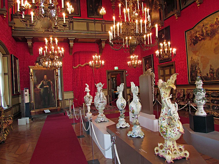 Prunksaal mit Kronleuchtern und einer Porzellansammlung