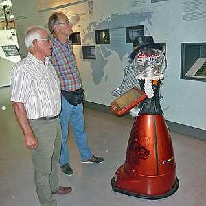 Museumsbesucher betrachten eine rote Karnevalsfigur